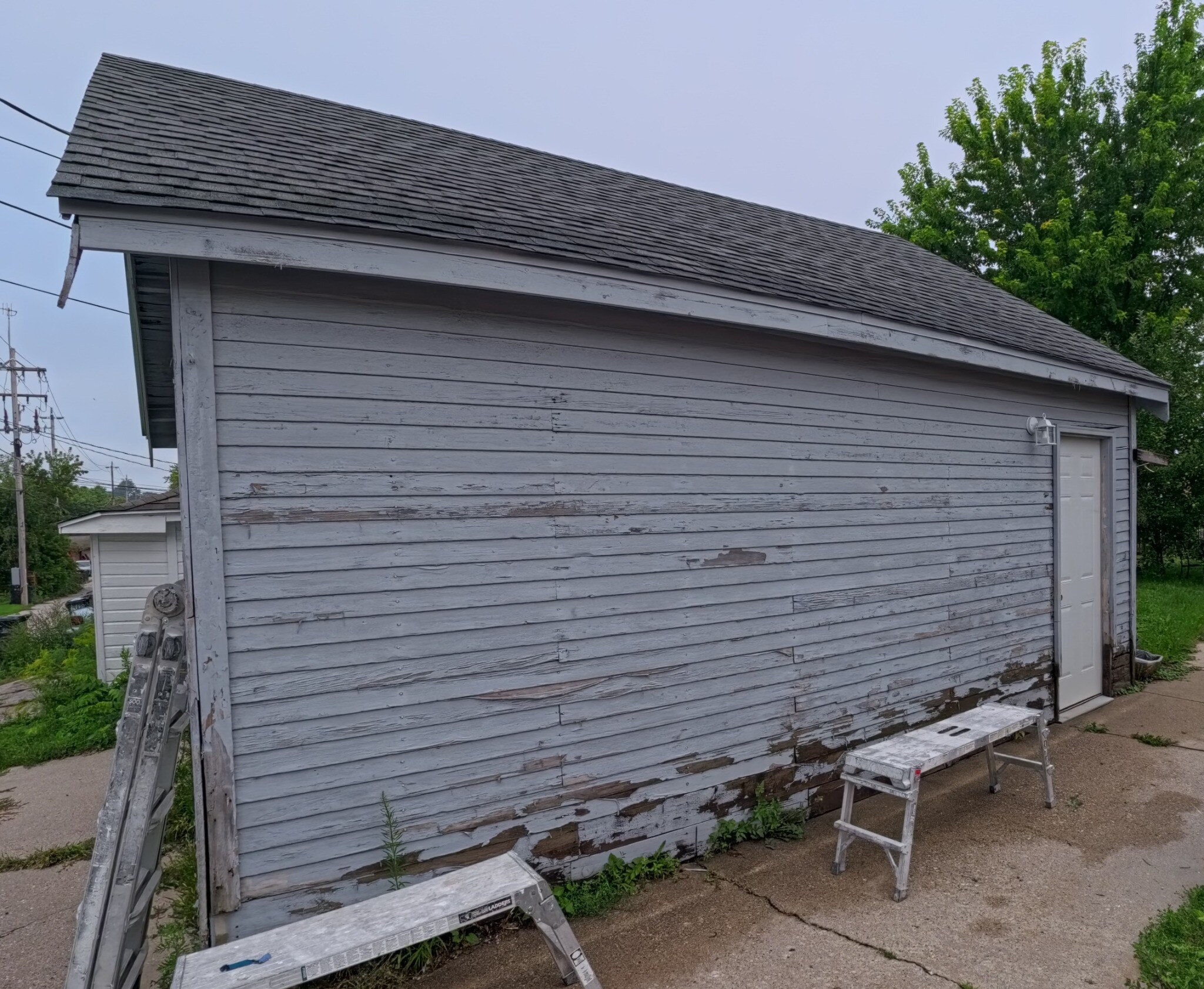 Detached garage with deteriorated horizontal siding before exterior renovation